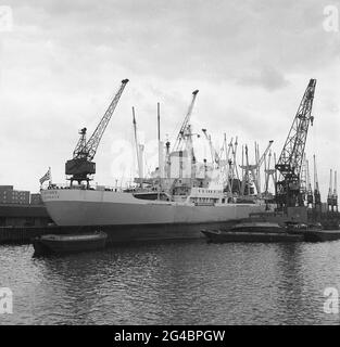 Années 1960, navire de fret grec historique, 'IKTINOS' amarré à Tilbury Docks sur la Tamise à Tilbury Essex, Angleterre, Royaume-Uni, une partie du port plus large de Londres. A côté de lui, la grue flottante de l'APL, London Léviathan, une barge de grue automotrice, construite à Amsterdam en 1965 pour l'Administration portuaire de Londres. On peut également voir un remorqueur de Mercantile Lightage Co. Le cargo IKTINOS a été construit en juillet 1969 par Doxford & Sunderland Shipbuilding & Engineering Co., Ltd., Sunderland, Royaume-Uni, pour Linées Interceanicas S.A. sous le drapeau grec. Banque D'Images