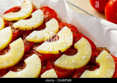 La combinaison de légumes et de fruits dans la nourriture. Cuisson des ananas avec des tomates. Une recette pour un délicieux plat pour une cuisson rapide à la maison. Les tranches d'ananas et les tomates sont prêtes à cuire. Vue de dessus Banque D'Images