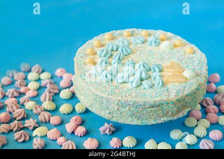 gâteau bleu avec bonbons pour la fête de la douche de bébé avec meringue. Gâteau fait maison pour un nouveau-né sur fond bleu. Banque D'Images