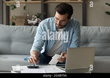 Jeune homme concentré des années 30 dans les lunettes de vue calcul des dépenses. Banque D'Images