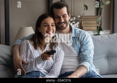 Un jeune couple de jeunes parents heureux et détendu regardant la télévision ensemble à la maison. Banque D'Images