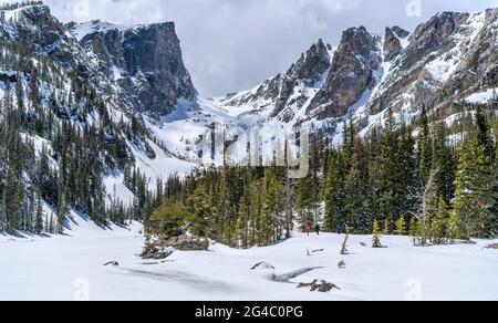 Spring Mountains - les lacs sont encore gelés à la fin de mai. Quelques braves visiteurs randonnée le long de Dream Lake couvert de neige vers des sommets élevés à RMNP, CO, États-Unis. Banque D'Images