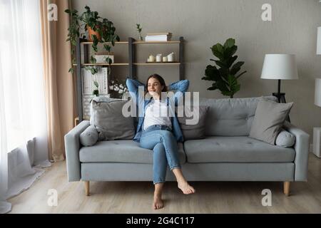 Une jeune femme heureuse se détendant sur un canapé confortable. Banque D'Images