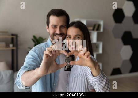 Un jeune couple de jeunes parents heureux et sincères montrant les clés de l'appareil photo. Banque D'Images