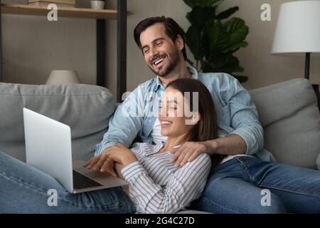 Joyeux couple de jeunes familles aimant regarder un film amusant sur ordinateur. Banque D'Images