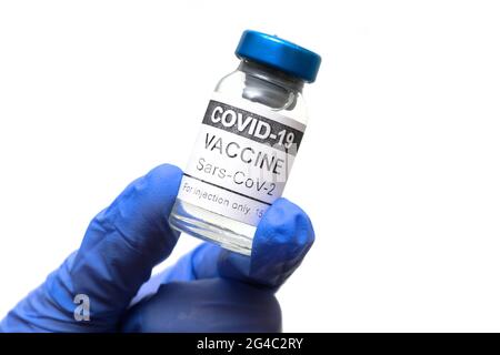 Flacon de vaccin COVID-19 isolé sur fond blanc, flacon de vaccin coronavirus dans une main gantée de médecin. Concept de vaccination, vaccination, v Banque D'Images