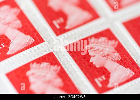 Gros plan rouge écarlate images de timbres de première classe Royal Mail pour l'affranchissement portant une image de la tête de la reine Elizabeth II, profondeur de champ étroite. ROYAUME-UNI Banque D'Images