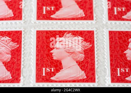 Gros plan rouge écarlate images de timbres de première classe Royal Mail pour l'affranchissement portant une image de la tête de la reine Elizabeth II, grande profondeur de champ. ROYAUME-UNI Banque D'Images