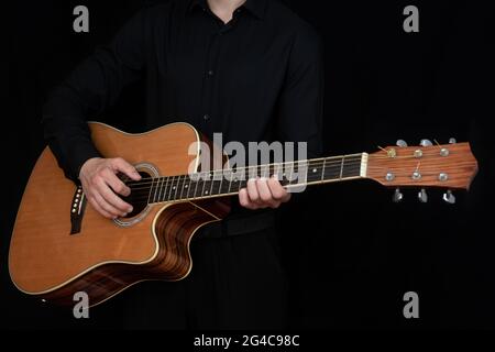 La main d'un homme tout en jouant une guitare électro-acoustique. Soufflez-le. Une main humaine joue la guitare. Guitariste d'école. Guitariste d'école Banque D'Images