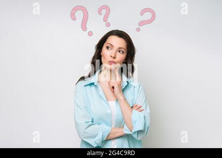 Une femme confuse se tient sans aucun doute, hausse ses épaules, ne peut pas donner une réponse à une question difficile, a une expression confuse sur son visage. Banque D'Images