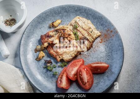 Steaks de porc avec tomates sur une assiette vue rapprochée d'en haut Banque D'Images