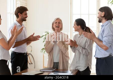 Des employés heureux applaudissent la direction d'une femme d'affaires d'âge moyen lors d'une réunion Banque D'Images