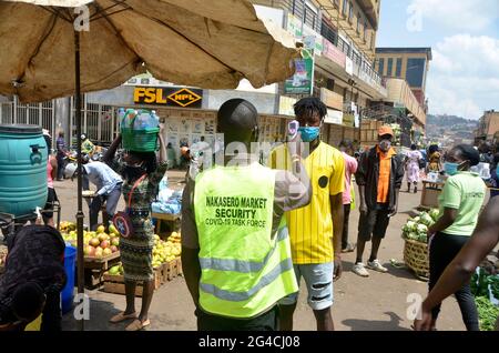 Kampala, Ouganda. 20 juin 2021. Un homme de sécurité mesure la température d'un homme à l'entrée d'un marché à Kampala, en Ouganda, le 20 juin 2021. Le Président ougandais Yoweri Museveni a annoncé vendredi une série de mesures visant à contenir la propagation rapide du nouveau coronavirus alors que le pays connaît une deuxième vague. Crédit: Nicholas Kajoba/Xinhua/Alamy Live News Banque D'Images