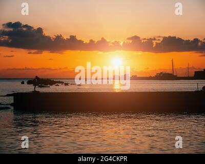 Complexe tropical au beau coucher de soleil coloré sur la surface de la mer et silhouette de brise-lames. Banque D'Images