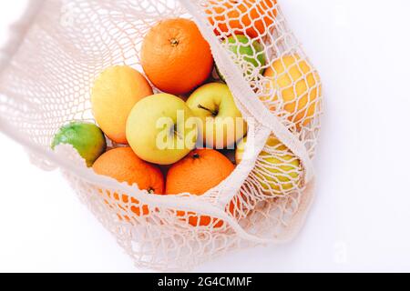 Sac en maille de coton avec fruits frais colorés sur fond clair, gros plan. Concept zéro déchet Banque D'Images