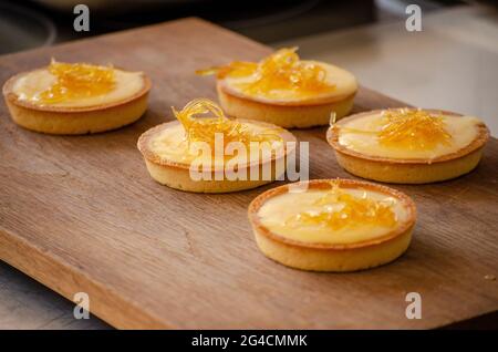 Vue sur les petites tartes jaunes de citron sur une planche à découper en bois dans la cuisine Banque D'Images