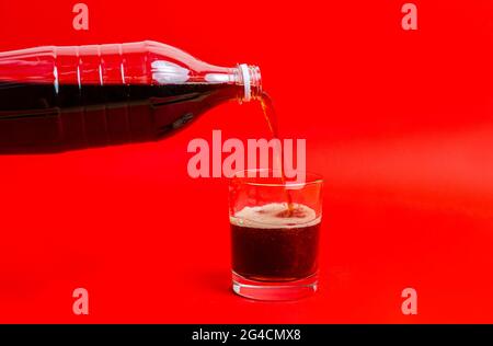 limonade noire versée dans le verre, bouteille de soda isolée sur fond de couleur Banque D'Images