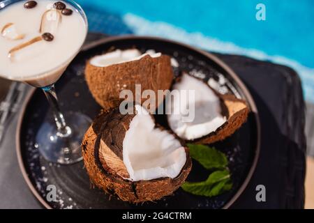 Vue de dessus du café dans une tasse avec des haricots servis sur un plateau à côté de la noix de coco. Rafraîchissements au bord de la piscine Banque D'Images