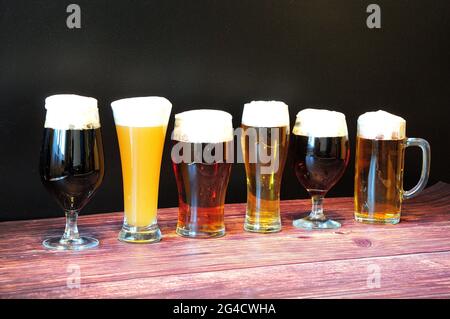 Six verres différents avec différents types de bière sont dans une rangée sur une table en bois. Gros plan. Banque D'Images
