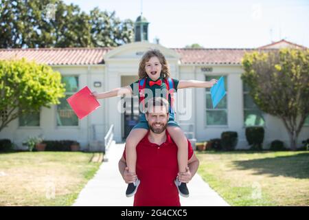 Garçon d'école allant à l'école avec père. Premier jour de l'automne. Papa et fils s'amusent près de la cour de l'école. Concept de famille amicale. Banque D'Images