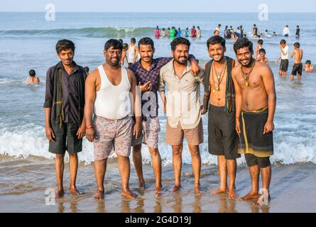 Photo de groupe de six hommes, trois vêtus de noir comme des dévotés d'Ayappa appréciant l'eau de lecture à la plage de Gokarna, Karnataka, Inde Banque D'Images