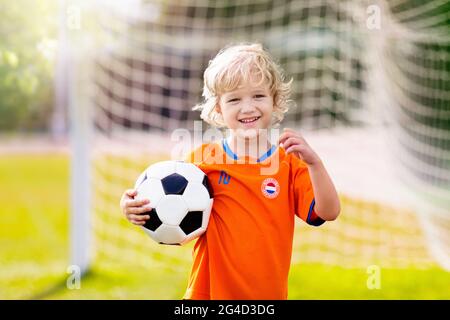 Les enfants hollandais jouent au football sur le terrain. Fans de l'équipe néerlandaise avec drapeau national. Allez en Hollande ! Les enfants ont un but au match de football. Enfant dans le drapeau jer Banque D'Images