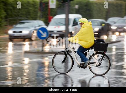 Hambourg, Allemagne. 21 juin 2021. Un cycliste portant un cap à pluie jaune traverse une intersection de feux de circulation à Lokstedt. Credit: Georg Wendt/dpa/Alay Live News Banque D'Images