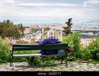 Un homme assis non identifié défoqué jouit de la vue depuis la colline de Lycabette. L'Acropole domine l'image, avec le golfe Saronique et le Pirée dans le Banque D'Images