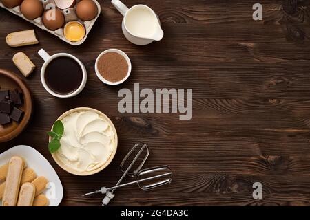 Produit pour la préparation du dessert tiramisu. Vue de dessus des ingrédients sur un panneau en bois brun foncé. Espace libre pour une inscription. Banque D'Images