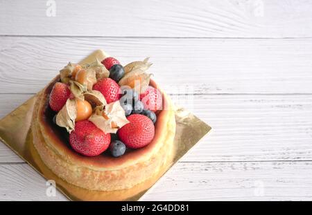 Gâteau au fromage grillé décoré de fraises aux fruits et de bleuets. Sur une table en bois blanc, copier l'espace. Banque D'Images