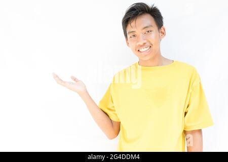 Joyeux indonésien gars debout avec chaque main sur la gauche comme s'il tenait quelque chose Banque D'Images