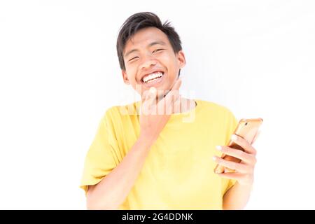 Un homme indonésien avec un téléphone se touchant avec joie son visage - le moment d'obtenir un message agréable Banque D'Images