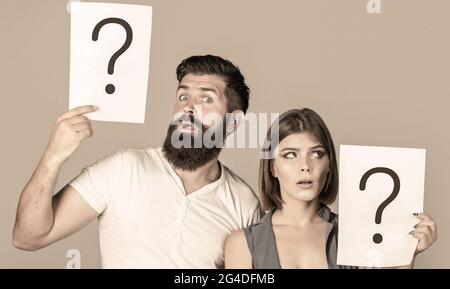 Des couples confus avec des points d'interrogation. Conflit entre deux personnes. Homme pensif et femme réfléchie, conflit. Portrait d'un couple tenant du papier Banque D'Images