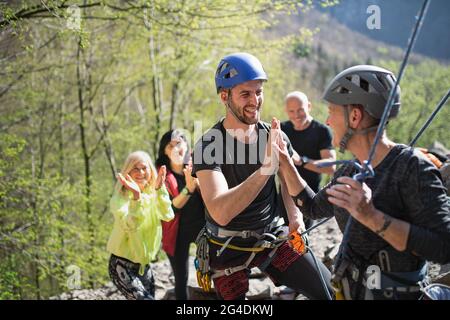 Groupe de personnes âgées avec instructeur grimpant des rochers à l'extérieur dans la nature, mode de vie actif. Banque D'Images