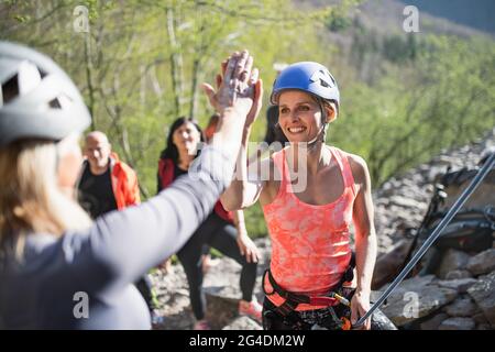 Groupe de personnes âgées avec instructeur grimpant des rochers à l'extérieur dans la nature, mode de vie actif. Banque D'Images