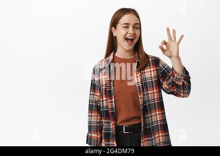 Bien, d'accord. Souriante, la jeune fille se moque et montre un bon signe, assurez tout bon, sous contrôle, en faisant des allusion à de grandes réductions, en se tenant Banque D'Images