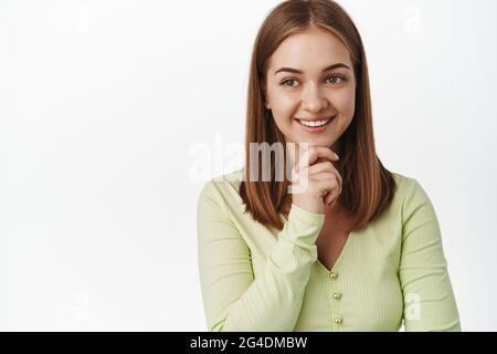 Gros plan de la jeune femme réussie réfléchie, souriant heureux, regardant de côté et lisant le texte promotionnel, regardez le logo satisfait, pensant, debout Banque D'Images