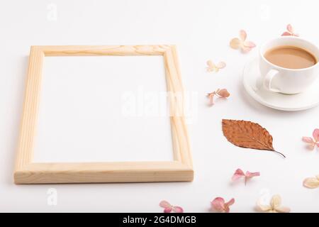 Composition avec cadre en bois, feuilles d'automne en hêtre brun, fleurs d'hortensia et tasse de café. maquette sur fond blanc. Vide, vue latérale, lif fixe Banque D'Images