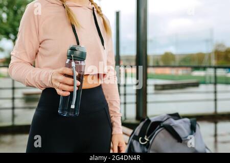 Jeune sportswoman avec bouteille d'eau et sac de gym Banque D'Images