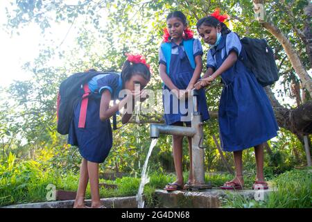 École rurale indienne les filles buvant de l'eau de tube bien au village Banque D'Images