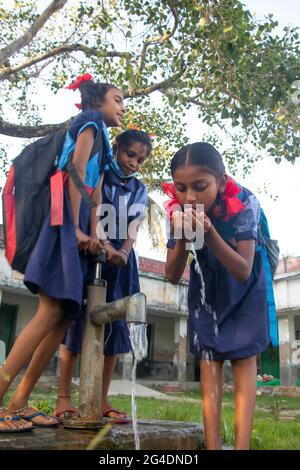 École rurale indienne les filles buvant de l'eau de tube bien au village Banque D'Images