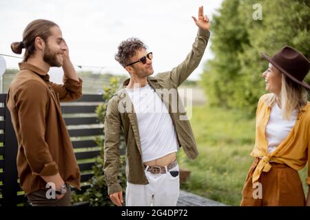 De jeunes amis adultes traînent, parlent et s'amusent ensemble dans la belle arrière-cour de la maison de campagne. Se reposer à l'extérieur et rencontrer des amis Banque D'Images