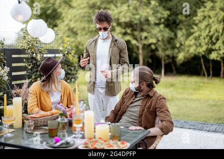 Amis en masque de visage repas à l'extérieur Banque D'Images