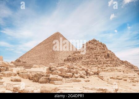 La pyramide de la reine à Gizeh contre le fond de la grande pyramide de Cheops. Beau ciel bleu ciel nuageux. Banque D'Images