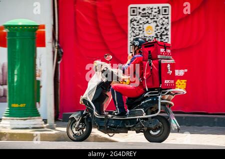 Un pilote de livraison KFC sur un scooter à l'intersection des routes d'Aomen et de Changhua près de la zone artistique M50 dans le district de Putuo, Shanghai, Chine. Banque D'Images