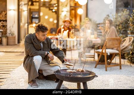 Homme grill avec un barbecue avec des amis à l'arrière-cour Banque D'Images