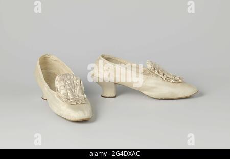 . Chaussure pour femme en satin blanc ivoire. Modèle : nez arrondi, une plaque et une couverture arrière. Le patin a une soupape relevée sur le marchepied. L'avant du talon s'abaisse. Le côté et l'arrière du talon sont ajustés et recouverts de satin blanc ivoire avec une bordure en cuir brunette depuis le rabat arrière. Arrière en cuir et semelle d'apprentissage. Feuille arrière doublée de cuir blanc ivoire, recouverte de linge beige. L'semelle intérieure est en blanc ivoire. Décoration: rosette en satin blanc ivoire au milieu de la couverture en laissant au sommet de la poignée sur le frotté. Pas de différence gauche/droite. Banque D'Images