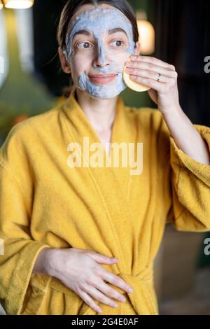 Femme retirant le masque de nettoyage de son visage Banque D'Images