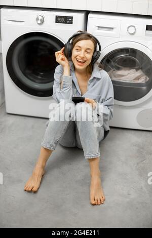 Femme aime la musique tout en lavant ses vêtements Banque D'Images