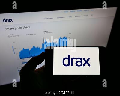 Personne tenant un téléphone portable avec le logo de la société britannique Drax Group plc sur écran devant la page Web d'affaires. Mise au point sur l'affichage du téléphone. Banque D'Images